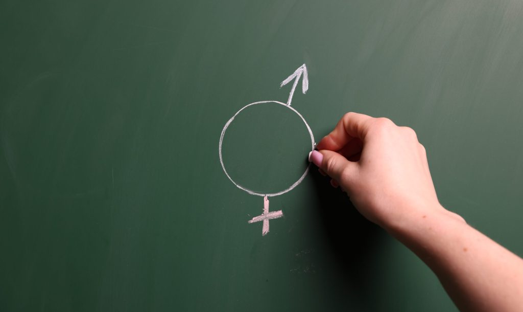 Sex Education. Woman drawing gender symbol on green chalkboard, closeup